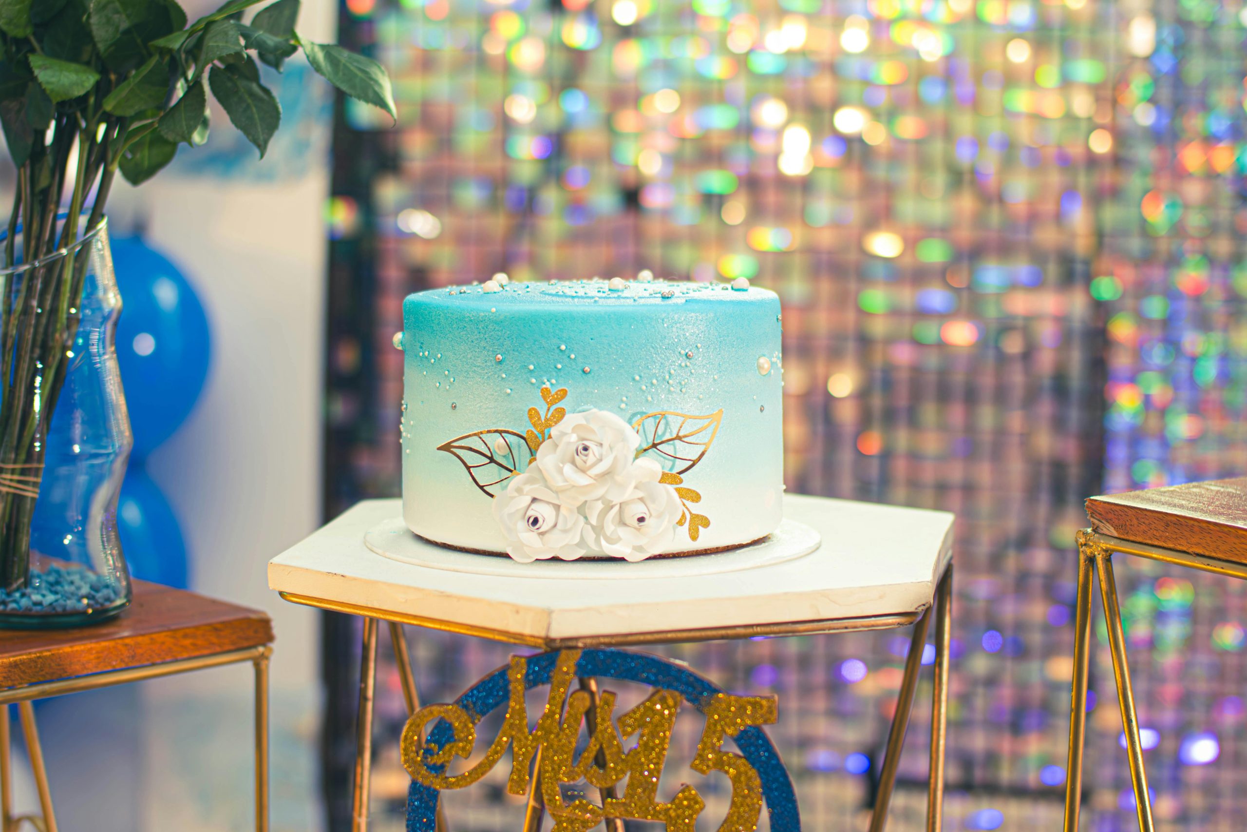 A blue gradient birthday cake with floral decorations on a festive table setup, perfect for celebrations.