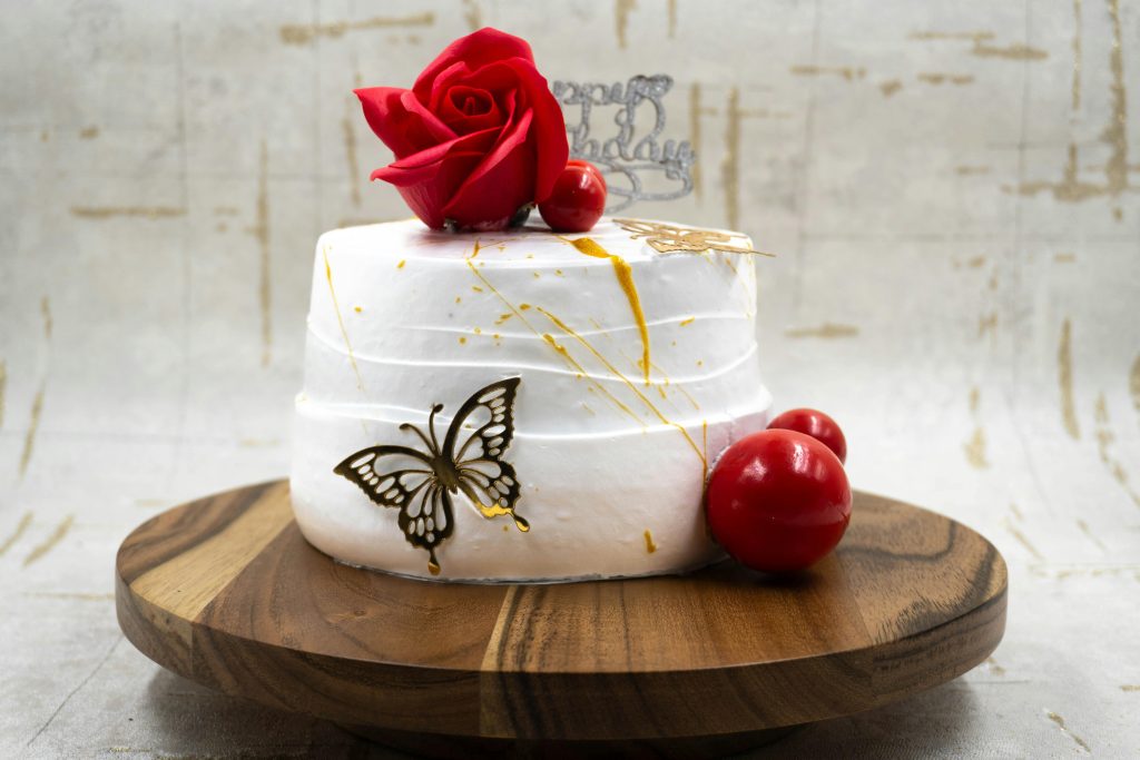 Stylish white cake decorated with a red rose, butterfly, and birthday message, perfect for celebrations.